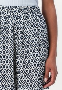 Navy and cream patterned skirt with a gathered waistband, featuring a geometric design and textured fabric. Hand partially visible.