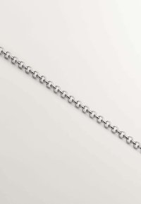 Cadena de metal plateado con formas circulares enlazadas, textura suave y un ancho constante, dispuesta plana sobre un fondo claro.