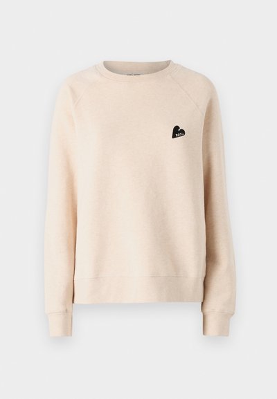 Sweatshirt beige à col rond avec des manches raglan. Présente un petit logo en forme de cœur noir sur la poitrine gauche. Tissu doux et texturé.