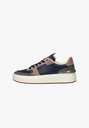 Navy leather sneakers with suede accents in brown and grey, featuring a thick white sole, round toe, and blue laces.