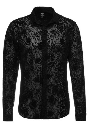 Chemise noire à manches longues avec des boutons, motif floral en velours et col classique, tissu semi-transparent, style masculin.