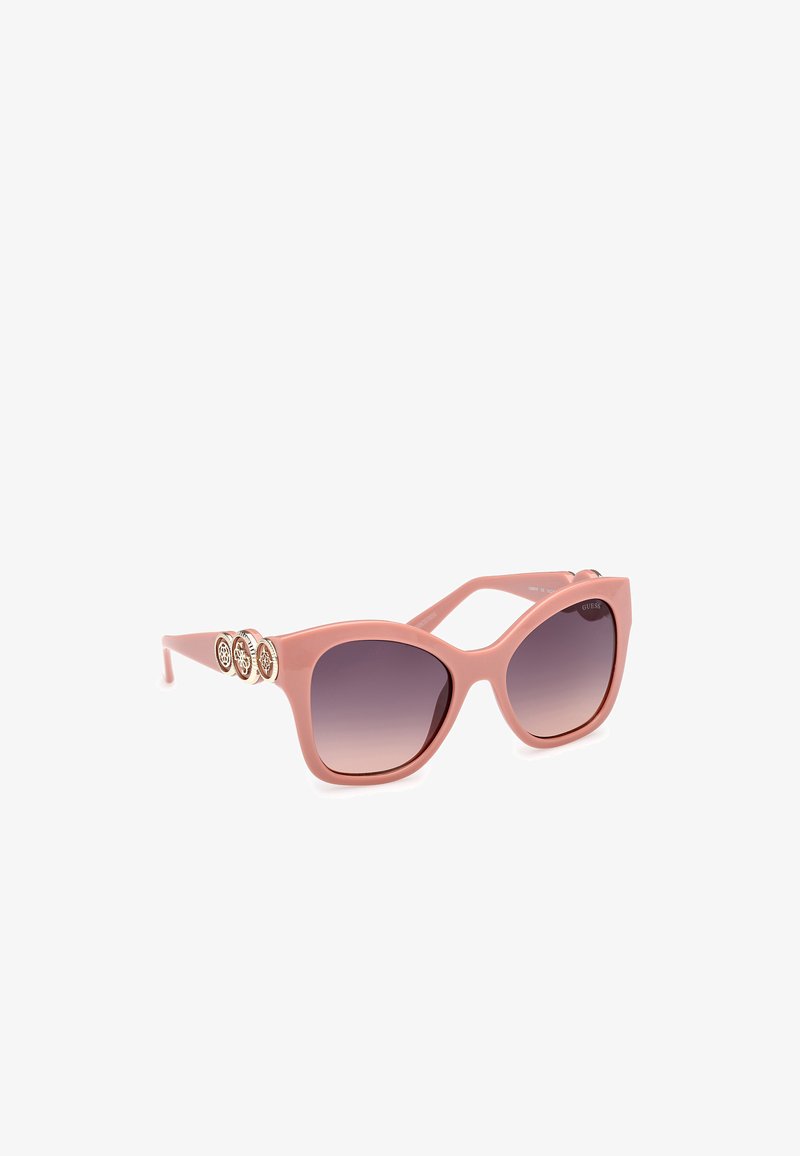 Roze plastic zonnebril met gradient lenzen, hoekige cat-eye vorm en drie decoratieve ronde accenten op de armen.
