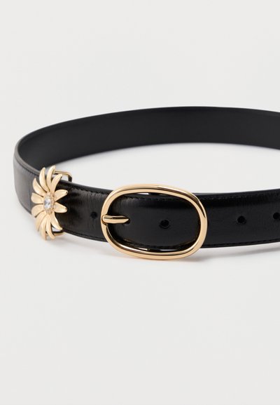 Μαύρη δερμάτινη ζώνη με οβάλ χρυσή αγκράφα και ένα μικρό χρυσό διακοσμητικό σε σχήμα λουλουδιού με καθαρό πολύτιμο λίθο κοντά στην αγκράφα.