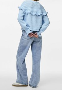 Pull en tricot bleu clair avec un ourlet volanté, un col côtelé et des manches ballon, associé à un jean en denim clair taille haute.