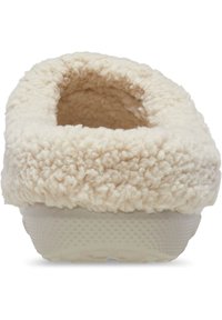 Crème-kleurige slipper met een donsachtig, textuur bovenwerk en een ronde opening, voorzien van een solide rubberen zool met een stippenpatroon.