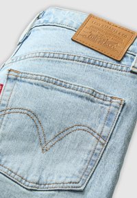 Lichtblauwe spijkerbroek van denim met een leren label met reliëfbranding, contrasterende oranje stiksels en een kenmerkend pocketontwerp.