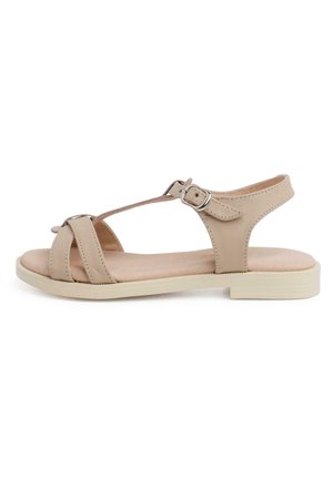 Beige leren sandaal met een platte zool, voorzien van twee kruisspellen en een enkelband die is beveiligd met een zilveren gespsluiting. Gladde textuur.