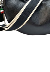 Zwarte leren tas met textuur in een ronde vorm, voorzien van een gestreepte zwart- en crèmekleurige schouderband en een klein Italiaans vlaggetje als hanger.