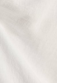 Tessuto morbido e bianco con una trama sottile e pieghe delicate che creano una superficie liscia e fluida.