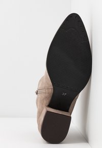 Bottine en daim marron avec talon bloc, fermeture éclair latérale et semelle en caoutchouc texturée. Taille 37 visible sur la semelle.