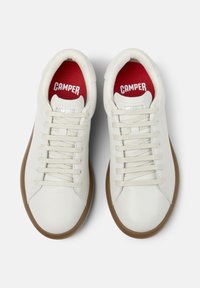 White sneakers with cream laces and brown soles, featuring a red insole with "CAMPER" text. The view is from above.