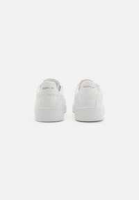 Hvite sneakers med en glatt skinnoverdel, polstret hæl og kontrastfarge gullmerke "REPLAY" bak. Minimalistisk design, flat såle.