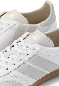 Baskets en cuir blanc avec bouts en daim beige, lacets blancs et semelles en gomme naturelle, avec marquage doré sur la languette.