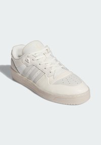 Białe skórzane sneakersy z perforowanym noskiem, trzema ukośnymi paskami i przezroczystą gumową podeszwą. Posiadają płaskie sznurowadła i wyściełany kołnierz.