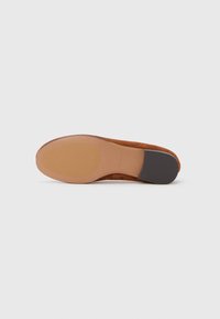 Brown suede flat shoe with a rounded toe, smooth tan rubber sole, and a black heel accent. Clean design with no additional embellishments.