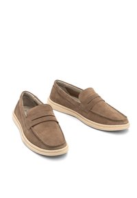 Mocasini din suede maro cu o talpă plată din cauciuc, având o cusătură și un detaliu cu curea frontală. Textură netedă și design cu vârf rotunjit.