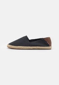 Espadrille-lignende sko med en mørkegrå kanvasoverdel, en brun lærhæl, og en vevd jutesåle. Sømløst design, lett vekt.