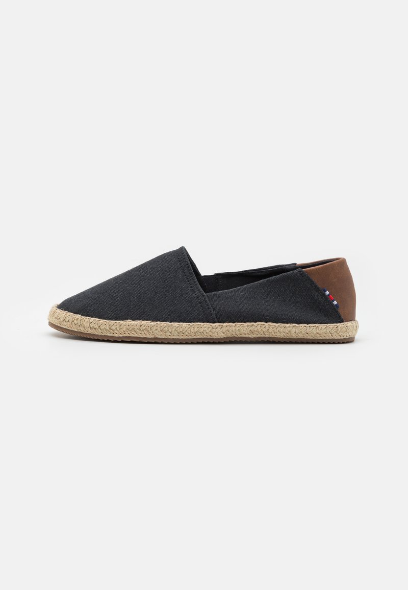 Espadrille-lignende sko med en mørkegrå kanvasoverdel, en brun lærhæl, og en vevd jutesåle. Sømløst design, lett vekt.