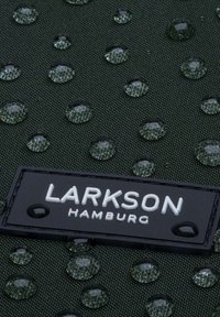 Tissu vert résistant à l'eau avec des gouttes d'eau en relief et une étiquette noire portant "LARKSON HAMBURG" embossée en texte blanc.