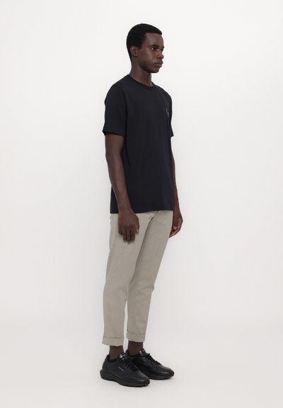 Tricou din bumbac negru cu mâneci scurte, pantaloni gri tapered și adidași negri. Design simplu, fără modele sau elemente metalice vizibile.