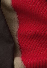 Tessuti con tessuto rosso a onde, combinato con materiali beige e grigio scuro. Texture liscia con motivi a contrasto.