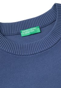 Niebieski sweter dzianinowy z ribbowanym kołnierzem i zieloną metką z napisem "UNITED COLORS OF BENETTON" wszytą wewnątrz dekoltu.