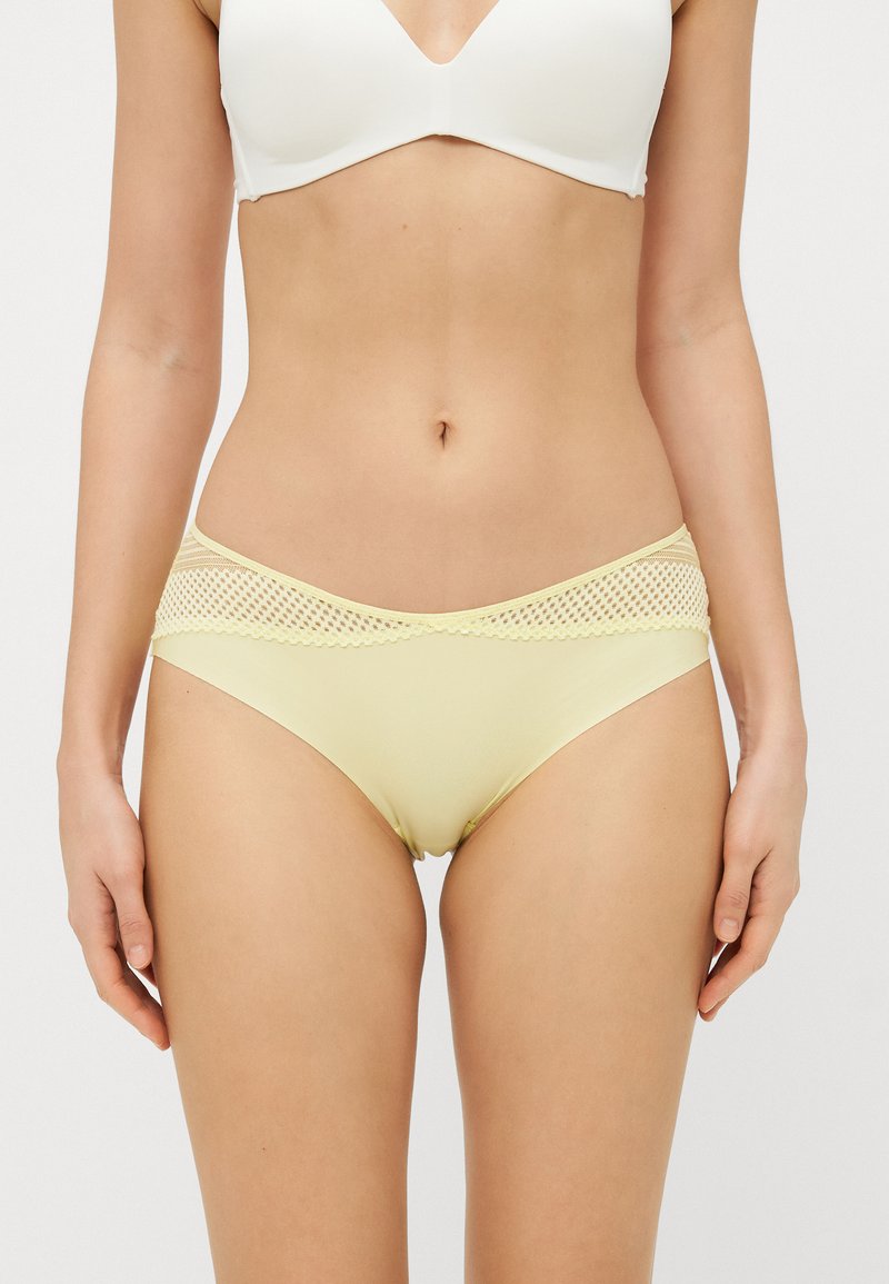 Világos sárga bikini alsó sima anyagból. Csipke díszítéssel a deréknál és klasszikus szabású.