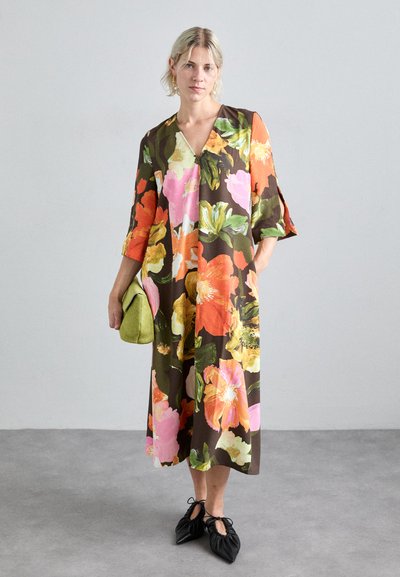 Blomsterkjole med levende oransje, rosa og grønne blomster på en mørkebrun bakgrunn. Midje lengde med trekvart ermer. Tilbehør inkluderer en grønn clutch.