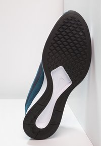 Černá gumová podrážka s texturovaným vzorem pro lepší přilnavost, horní část z semiše ve světle modré a tmavě modré barvě, elegantní design, bílá mezipodešev.