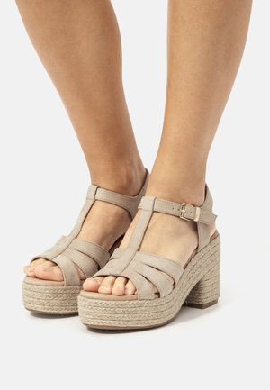 Sandali con tacco beige con design a T, realizzati in morbido camoscio, con una piattaforma in stile espadrilles intrecciata e una cinghia alla caviglia con fibbia.