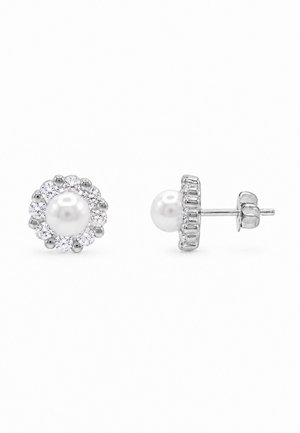 Une paire de boucles d’oreilles en argent à puce, avec des perles blanches au centre entourées de pierres précieuses transparentes ; l’une est montrée de face et l’autre de côté.