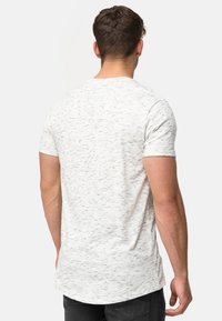 Herren T-Shirt mit kurzen Ärmeln in Hellgrau mit einem gesprenkelten Muster. Hergestellt aus weichem Stoff, verfügt es über einen abgerundeten Saum und ein figurbetontes Design.