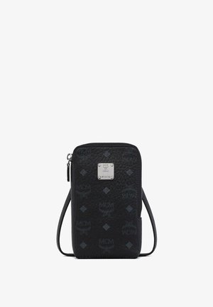 Sac bandoulière noir texturé avec logos MCM, motifs en losange, fermeture éclair et plaque métallique argentée portant l'inscription "MCM München M1978".