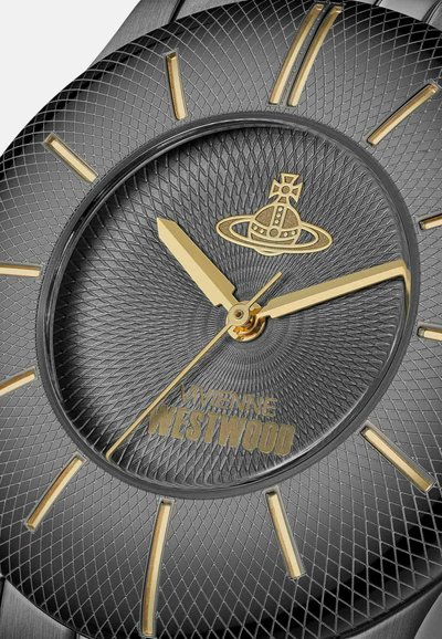 Quadrante dell'orologio nero textured con indici orari e lancette dorate. Presenta un logo centrale e un motivo a raggiera che si irradia dal centro.