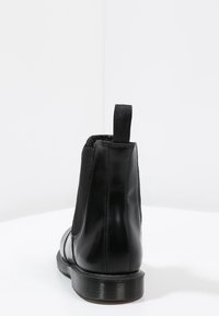 Botín negro de cuero con paneles laterales elásticos, punta redondeada y suela de goma texturizada. Cuenta con una lengüeta en la parte posterior.