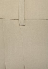Beige fabric swatch featuring a smooth texture with a visible seam and stitching detail. The material appears structured and durable.