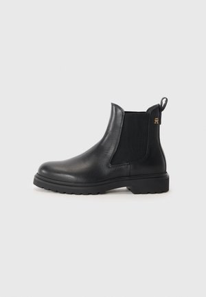 Botas Chelsea de cuero negro con paneles laterales elásticos, puntera redondeada y suela de goma texturizada. Acento del logotipo dorado en el lateral.