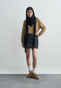 Pruun kudum, must sall, teksamini seelik, valged sokid ja pruunid karvase voodriga saapad. Minimalistlik disain ja neutraalsed värvid.