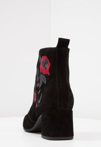 Czarne zamszowe botki za kostkę na słupku. Ozdobione czerwonym i szarym haftem kwiatowym. Posiadają pętelkę do łatwego zakładania.