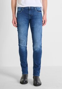 Uske slim-fit traperice u srednje plavoj boji, s izblijedjelim završetkom, dizajnom s pet džepova, metalnim detaljima i kontrastnim šavovima.