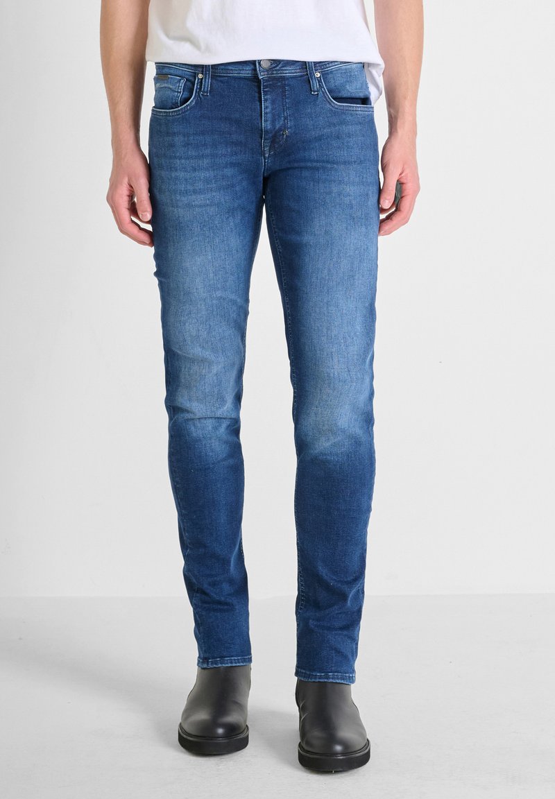 Uske slim-fit traperice u srednje plavoj boji, s izblijedjelim završetkom, dizajnom s pet džepova, metalnim detaljima i kontrastnim šavovima.