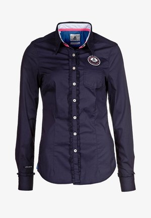 Navy blue long-sleeve shirt made of cotton, featuring a button-up front, ruffled details, a chest pocket, and an embroidered logo patch.