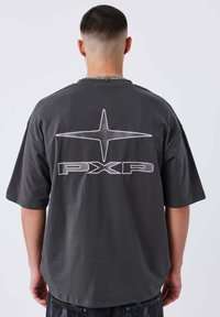 Camiseta de gran tamaño en gris oscuro con una gran estrella blanca y el logo "PXP" en la parte trasera, hecha de algodón suave y con mangas cortas.