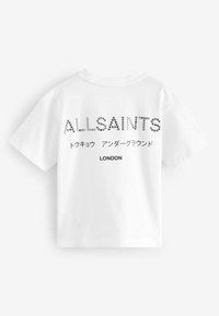 Bílá bavlněná trička s krátkým rukávem, s velkým grafickým textem "ALLSAINTS" z stříbrných hřebíků, s dalším textem v japonštině a "LONDÝN" níže.