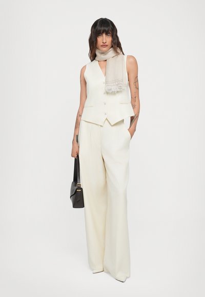 Off-white tailored vest with a V-neck, paired with wide-leg trousers. Accessorized with a light gray scarf and a black bag. Smooth, structured fabric.