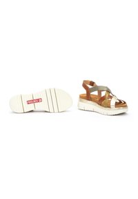 Sandalias con tiras de cuero en marrón, dorado y plateado, con plantilla acolchada y suela gruesa de goma blanca. Presenta un logo de la marca en la suela.