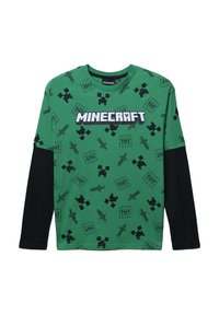 T-shirt verde a maniche lunghe di Minecraft con grafiche pixelate nere, tra cui strumenti e personaggi, con il testo "MINECRAFT" ben in evidenza.