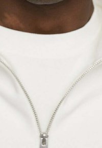 Giacca bianca con zip, caratterizzata da una chiusura con zip argentata, texture liscia e design minimalista. Il colletto è arrotondato, enfatizzando la semplicità.