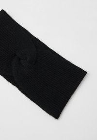 Fascia per capelli nera lavorata a maglia con un dettaglio a nodo torcigliante, caratterizzata da una texture a coste e una finitura liscia.