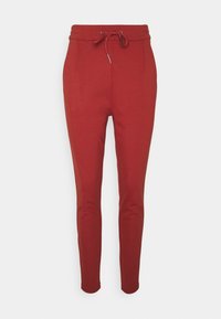 Röda smal tapered joggers tillverkade av mjukt tyg med snörning i midjan, två sidofickor och en slät, strukturerad yta.